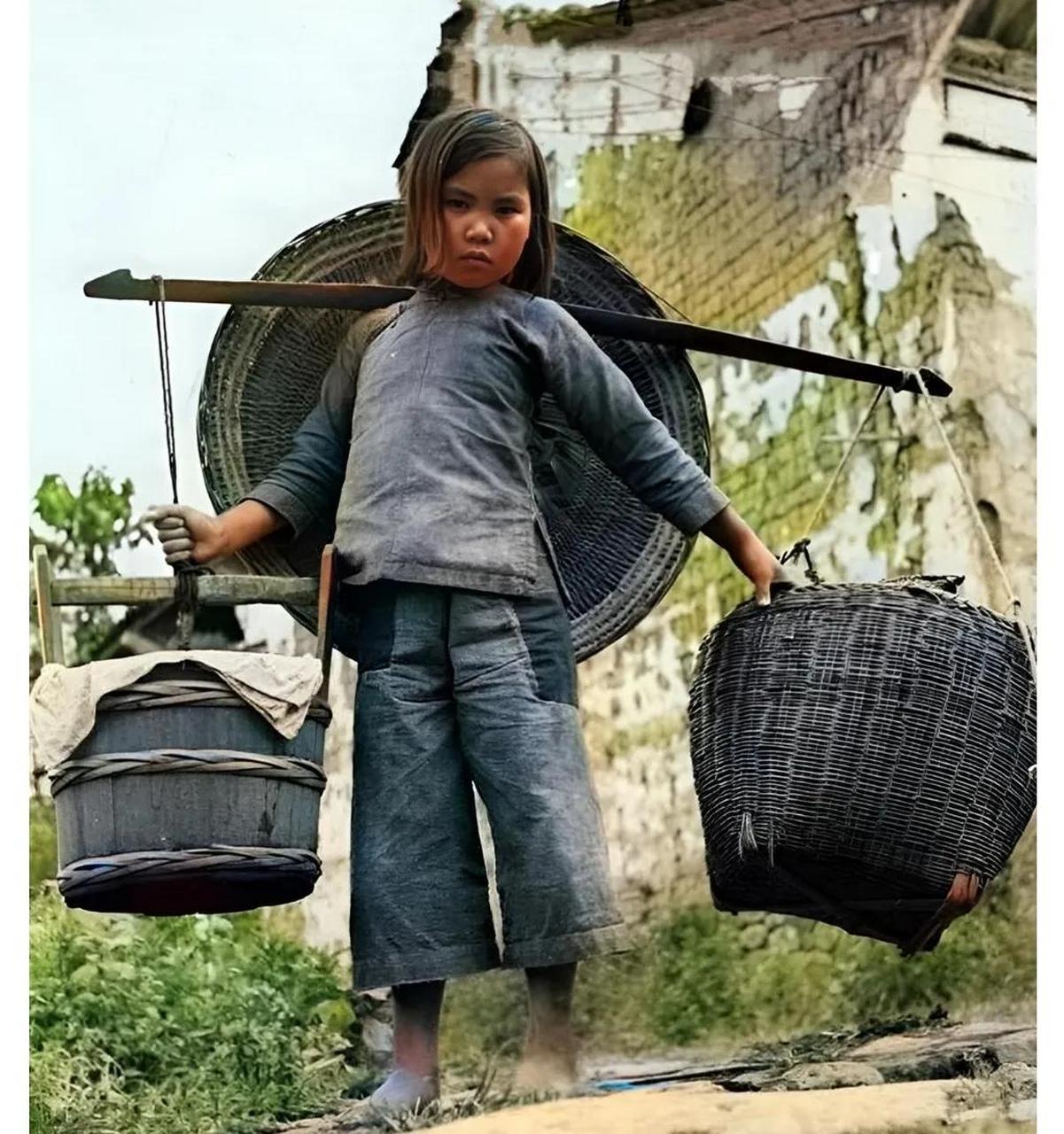 1944年,云南腾冲,一名小姑娘正挑着沉重的担子穿梭在