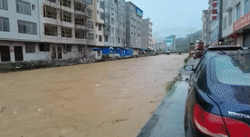 房屋内的电动车等物品被洪水冲出屋外, 一名男子差点也被洪水冲走