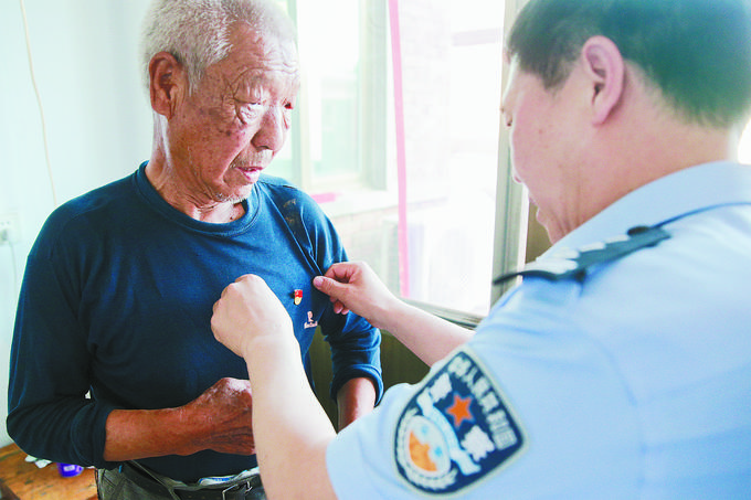 6月17日,西柏坡中心派出所民警为辖区北庄村74岁老党员佩戴党徽.