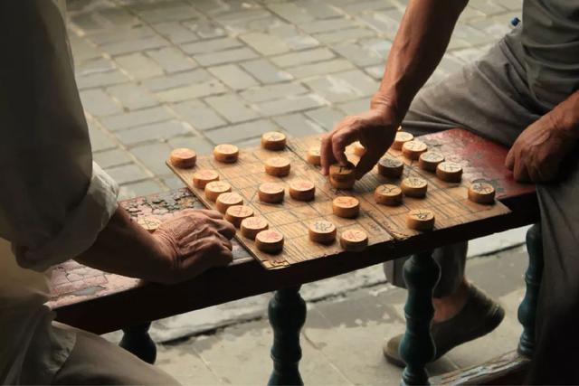 老人下棋從不認輸,看客常幫對手出主意,他氣急在棋盤貼上兩行字