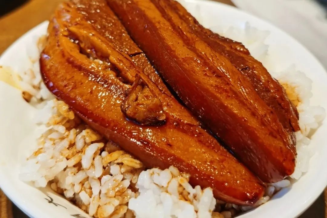 被炖到的把子肉得趁热连肉带汁盖在米饭上,接着用勺子把肉给捣进饭里