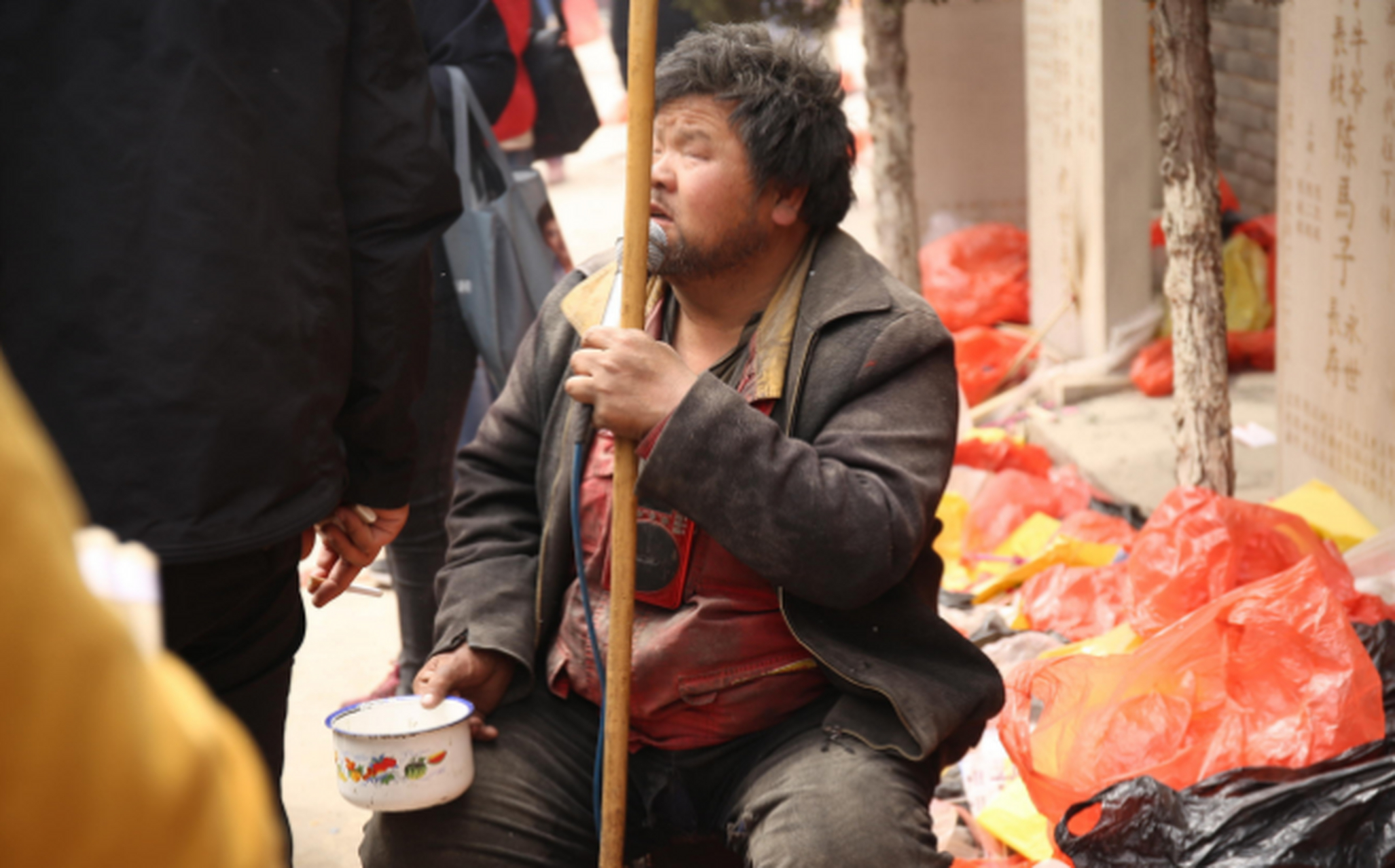 一个盲人乞丐戴着墨镜在街上行乞