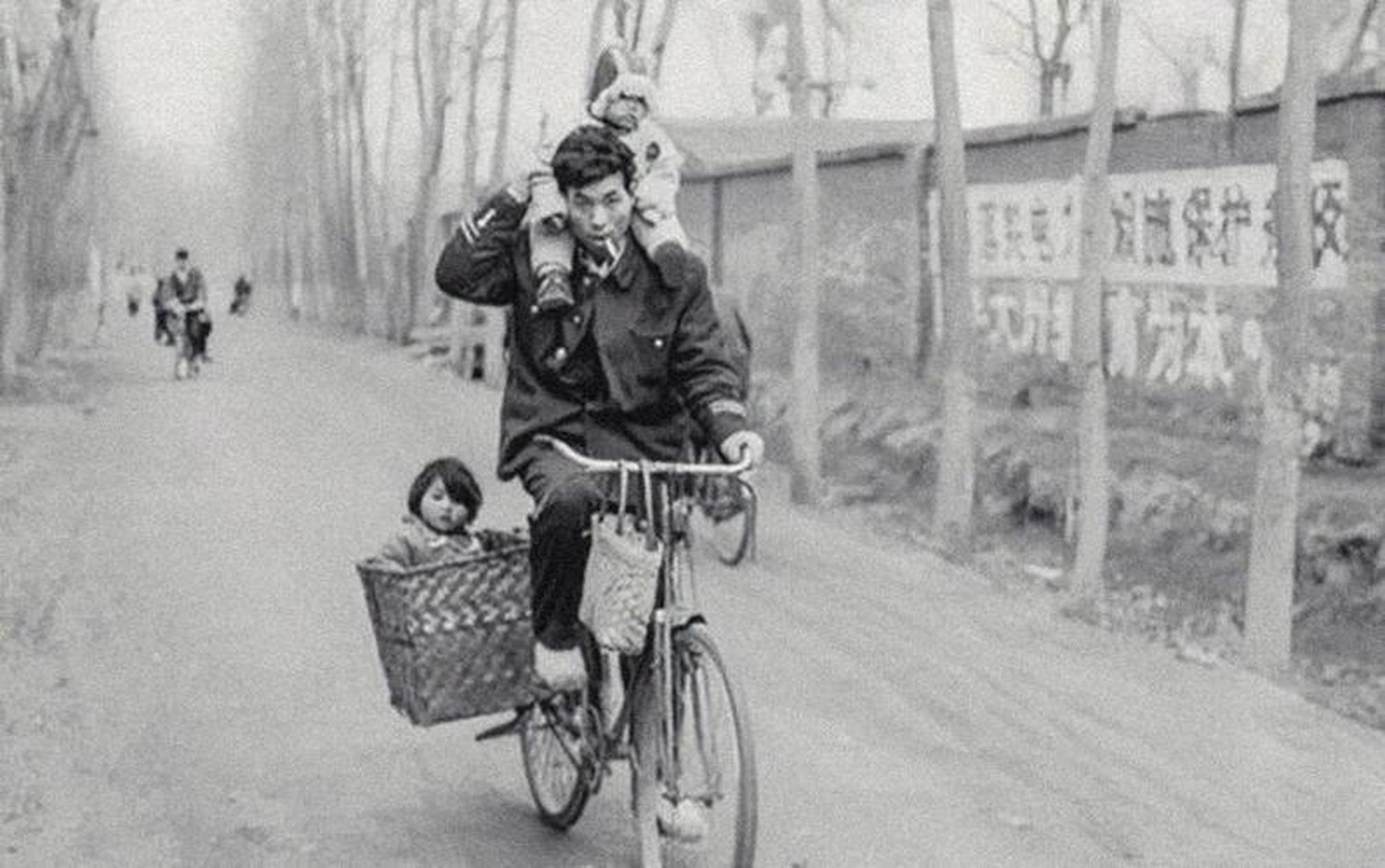 一张上个世纪八十年代的老照片,照片中的父亲一手扶着肩上的孩子,而