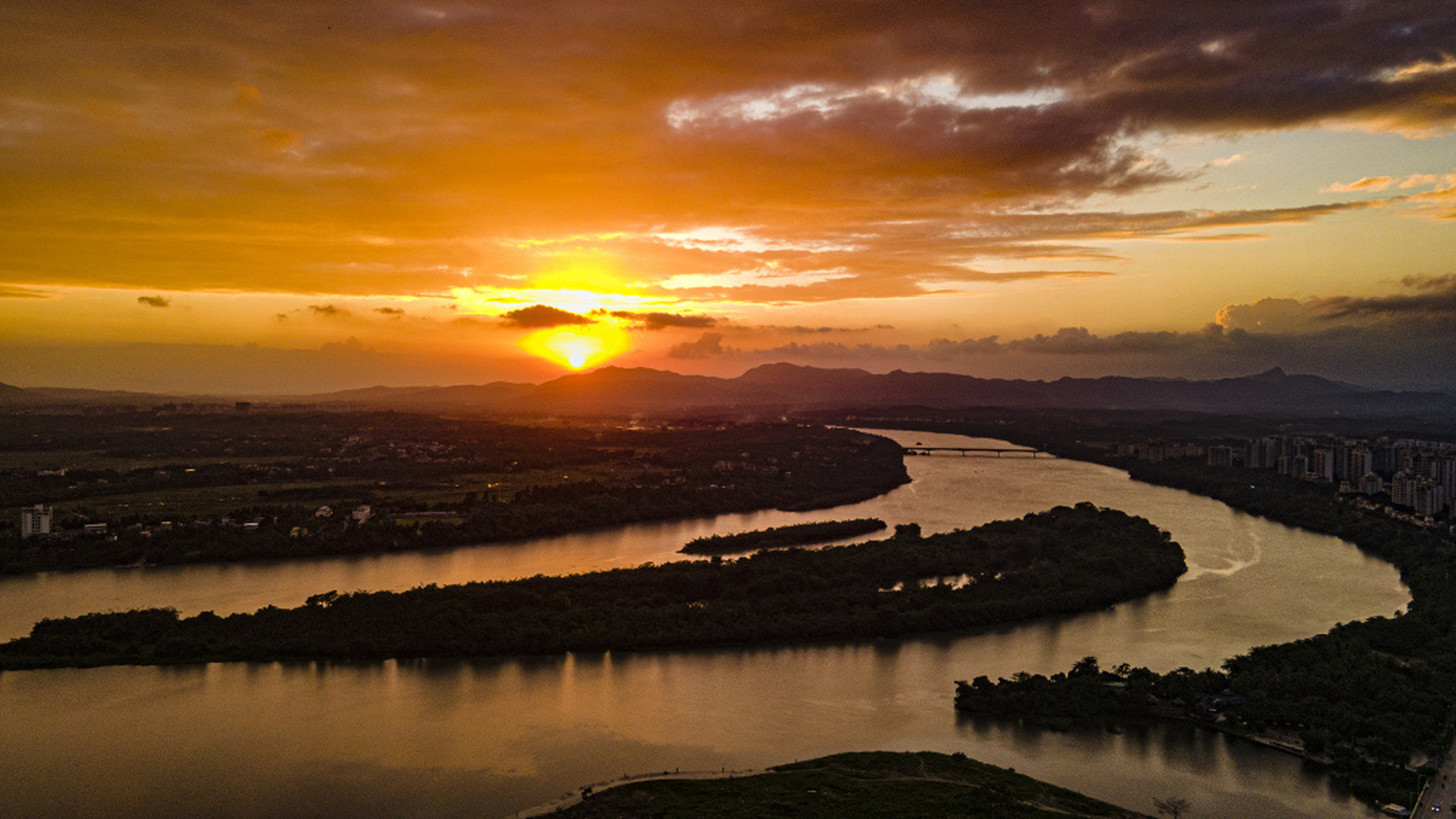 日暮时分,海南万泉河畔,太阳渐渐落下,将天边晕染成一片橘红,画面唯美