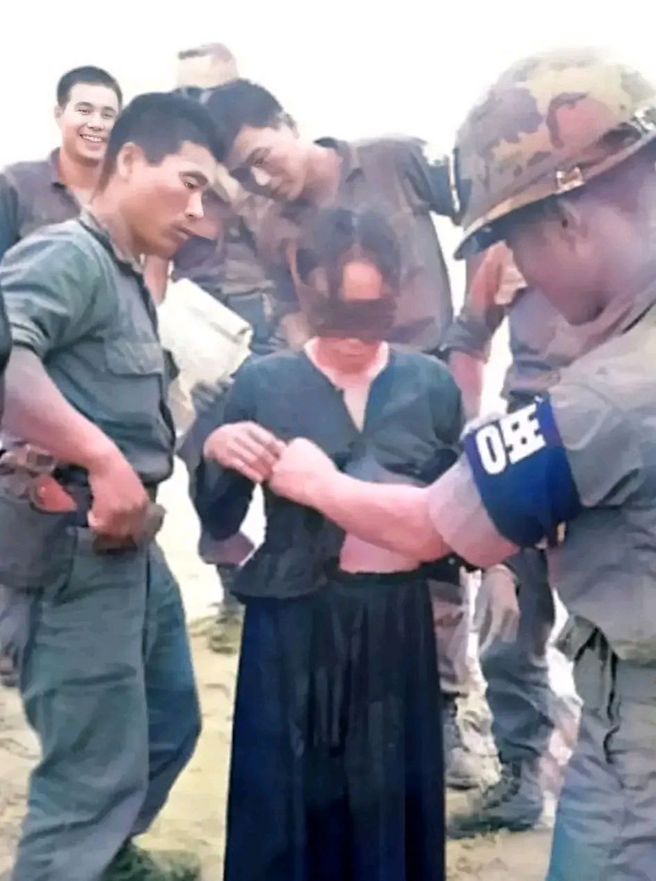 一群士兵在调戏一名被俘的北越妇女,这些人不是美军,而是帮助美国大兵