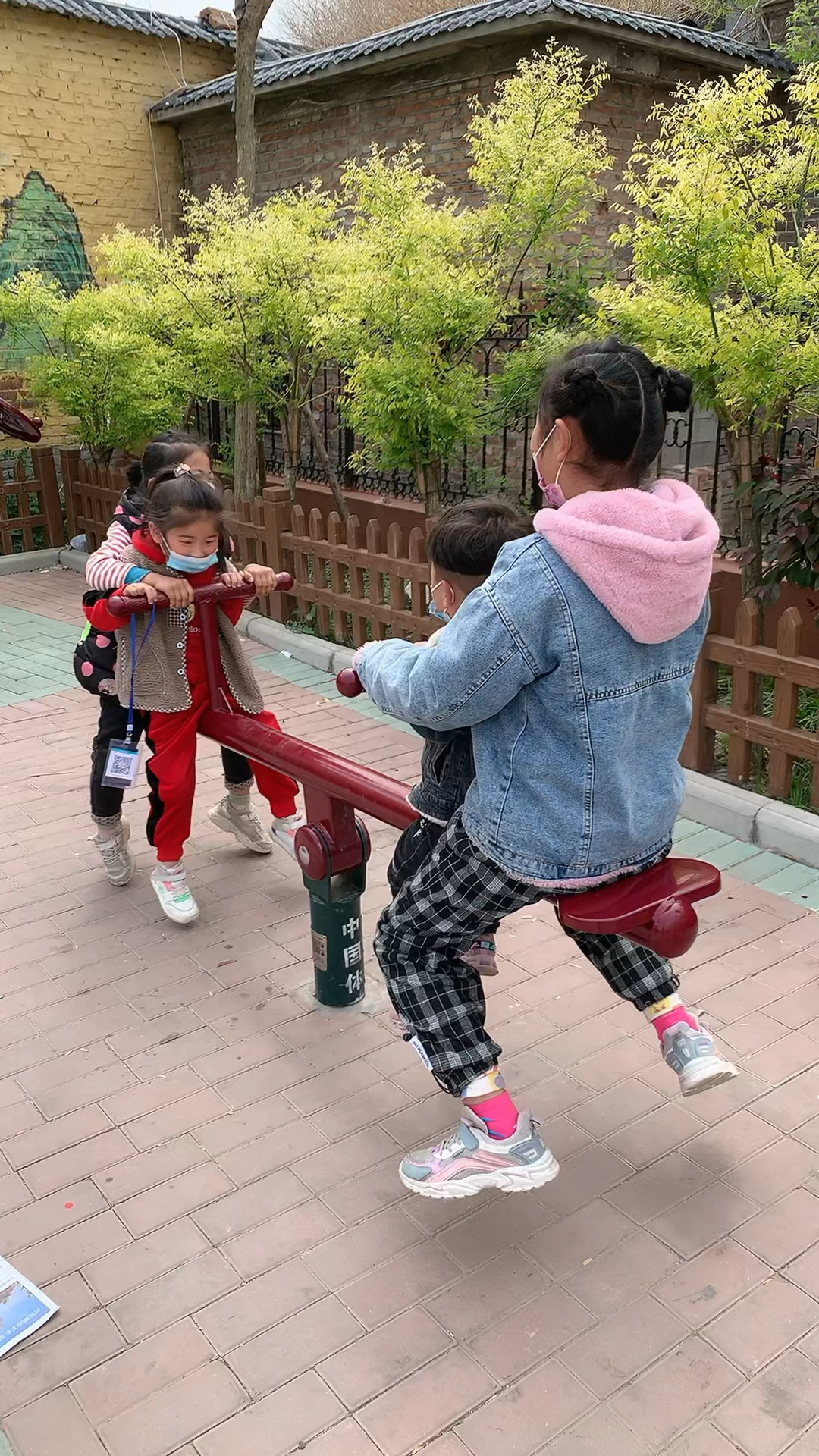 四个小宝贝在公园玩跷跷板,玩嗨了