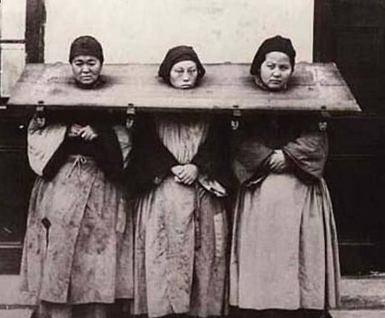 晚清老照片: 一副枷锁,锁着三名女囚犯.