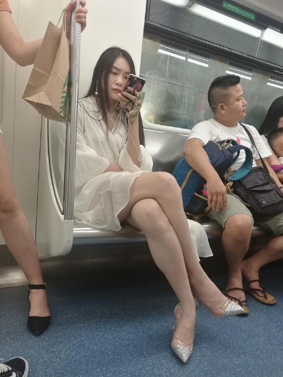 上海市的地铁里,一个身穿短裙的美女正玩着手机.