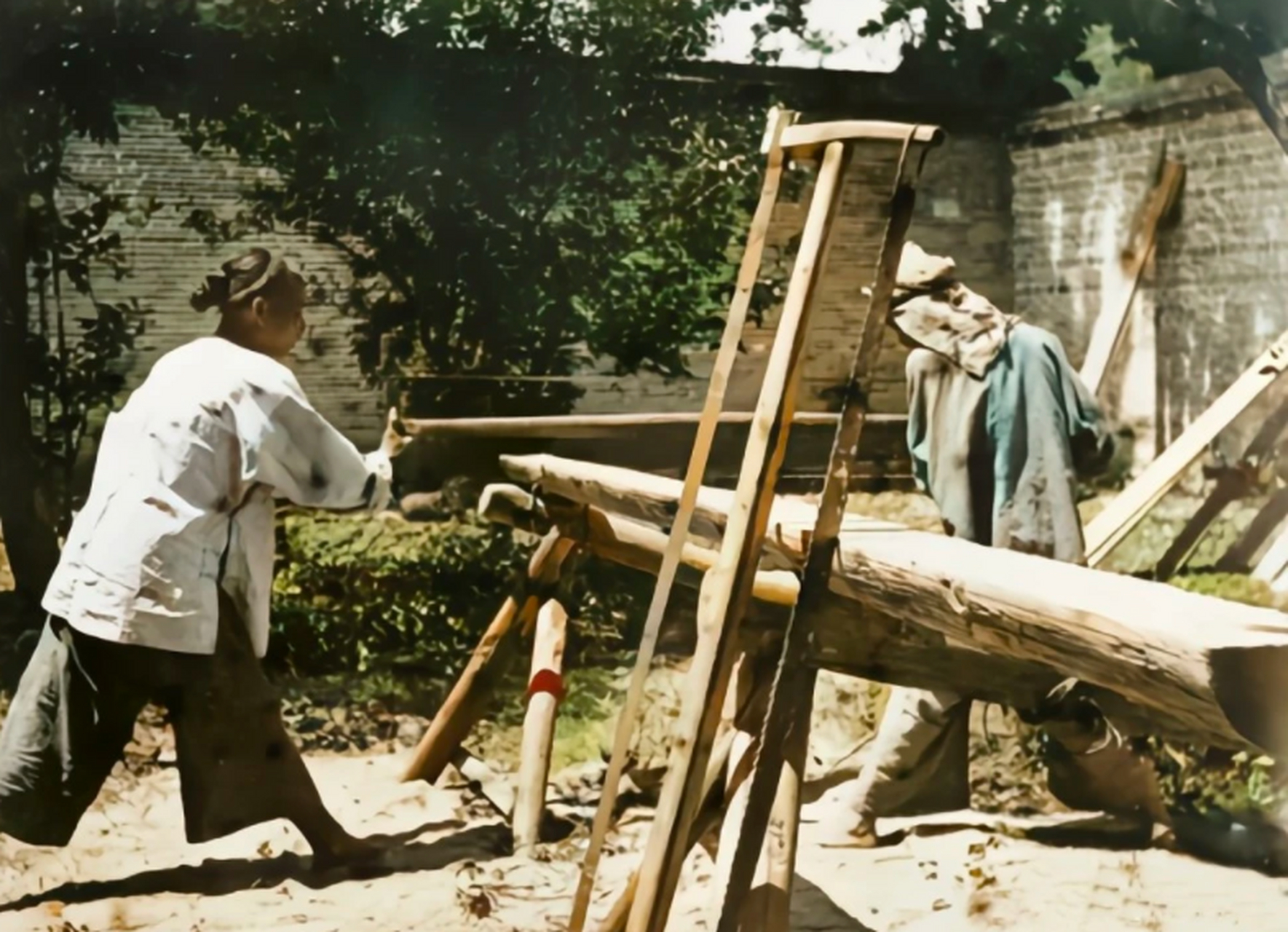 清朝老照片:两个木匠在奋力地锯着木头