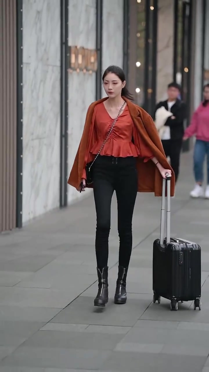 橘色上衣搭配黑色紧身裤和棕色外套,小姐姐的穿搭时髦又帅气
