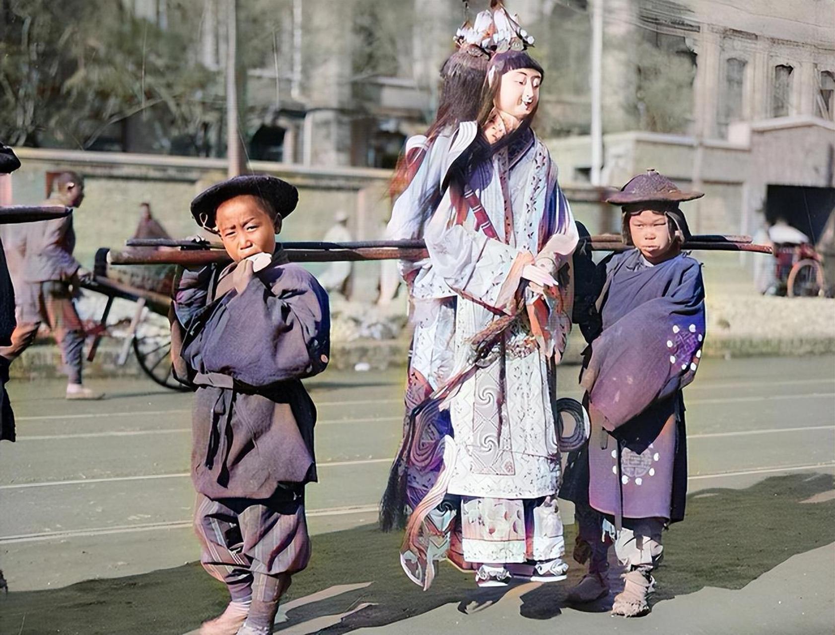 这是一张晚清时期的上色照片,图中两名孩童扛着一对纸人,他们是殡葬