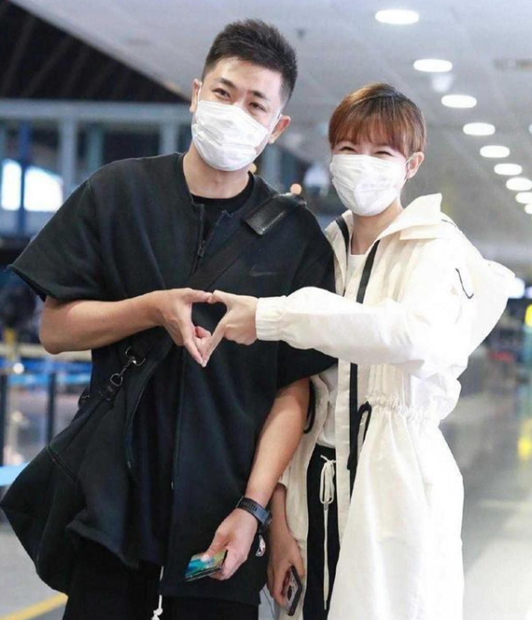 李艾牵手老公走机场,高调比心秀恩爱,低调穿黑白配造型超有范.