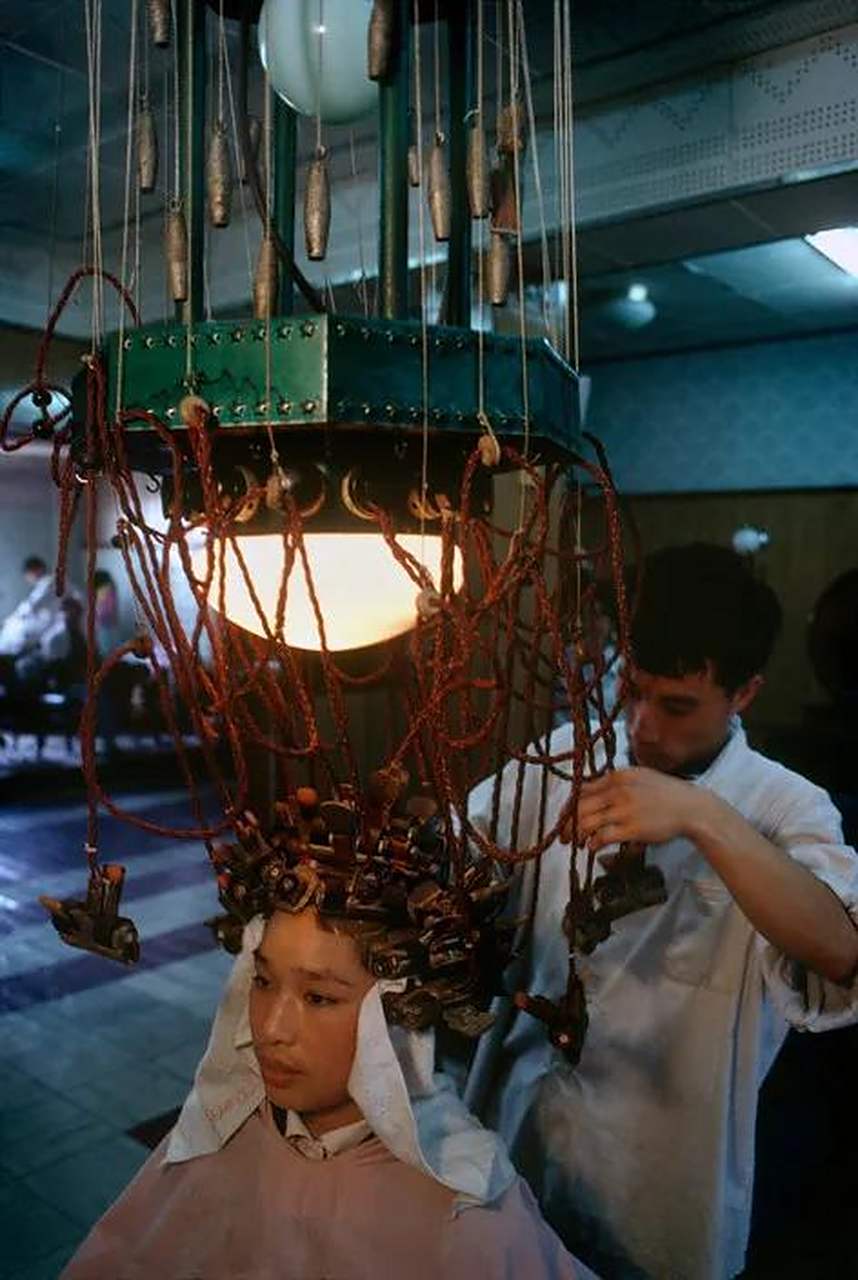 上海,1980年代,一位年轻女子身处理发店,正在烫着头发.