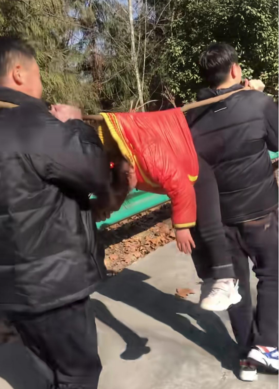 两个大人用木棍抬着小朋友下山,抱着不好么,看着真危险