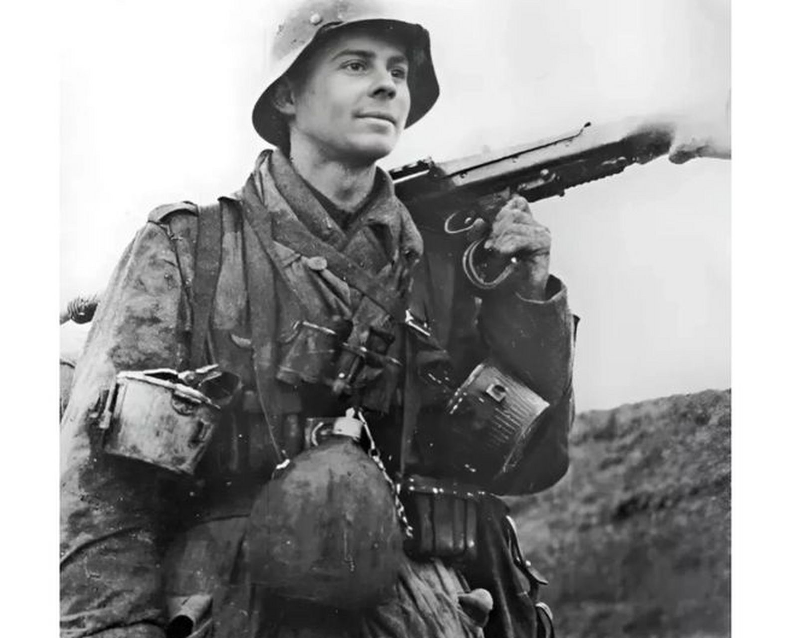 在二战期间,一名看上去年轻的德国士兵,带着一挺mg42机枪兴高采烈地
