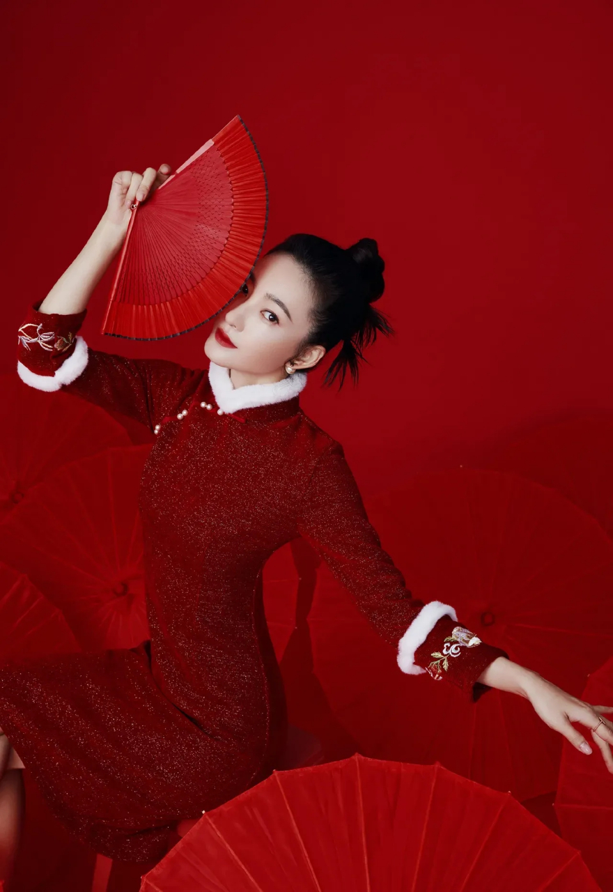 王丽坤手拿折扇,穿一袭酒红色中国风旗袍,袖口和领口白色貂毛点缀