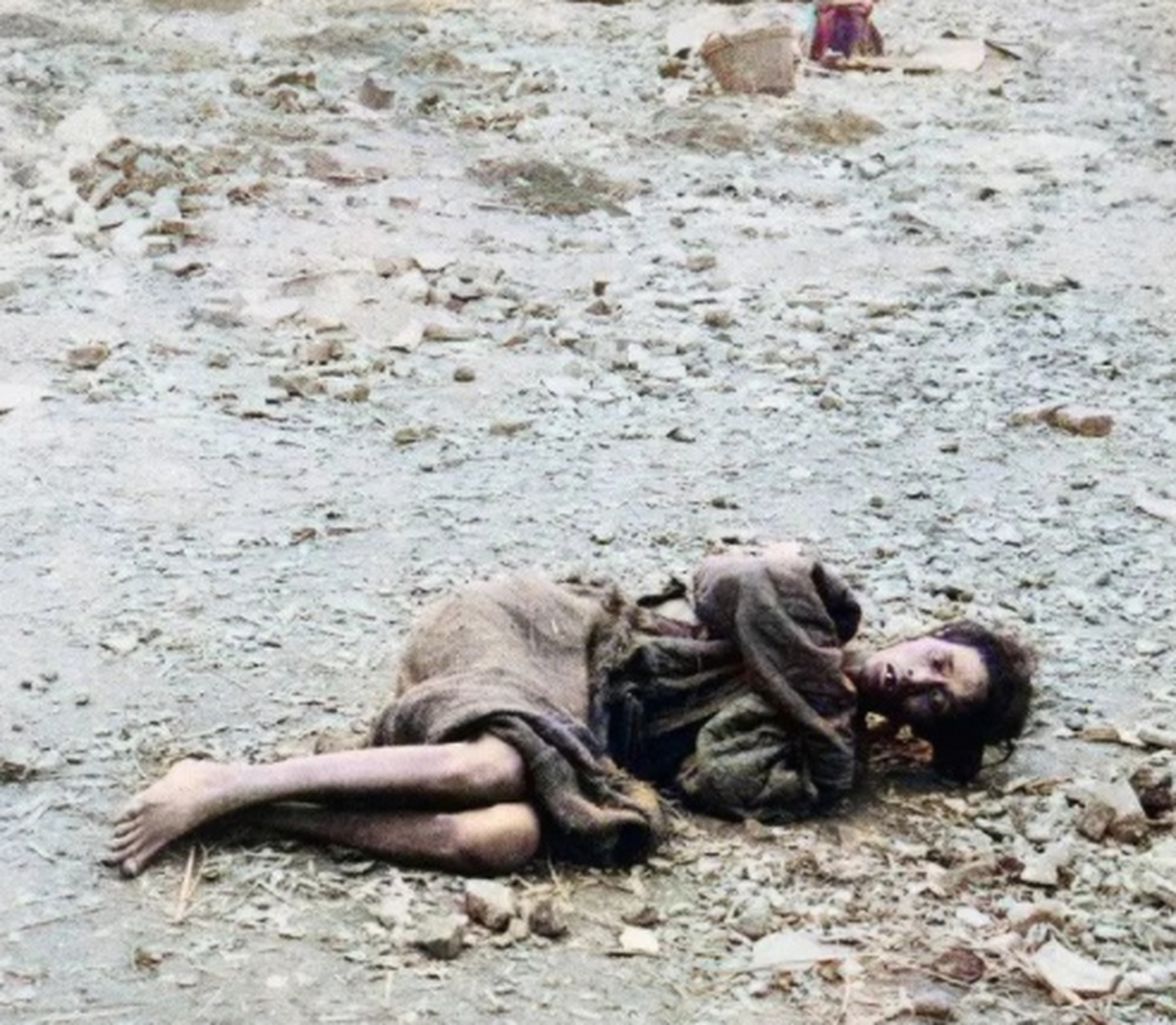 一名穿着衣衫褴褛的女子呈卷曲状躺在地上,由于连续