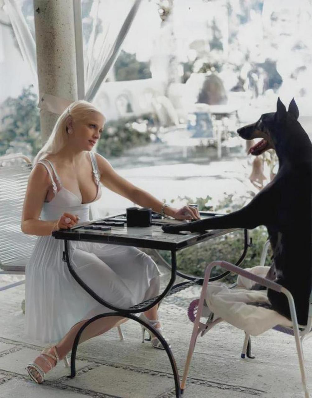 年轻时的麦当娜和她的小狗一同坐在桌子旁,它们互相凝视着,仿佛二者都