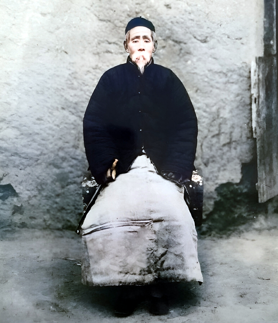 老人头戴瓜皮帽,身穿棉长袍,手中持一根长烟杆.