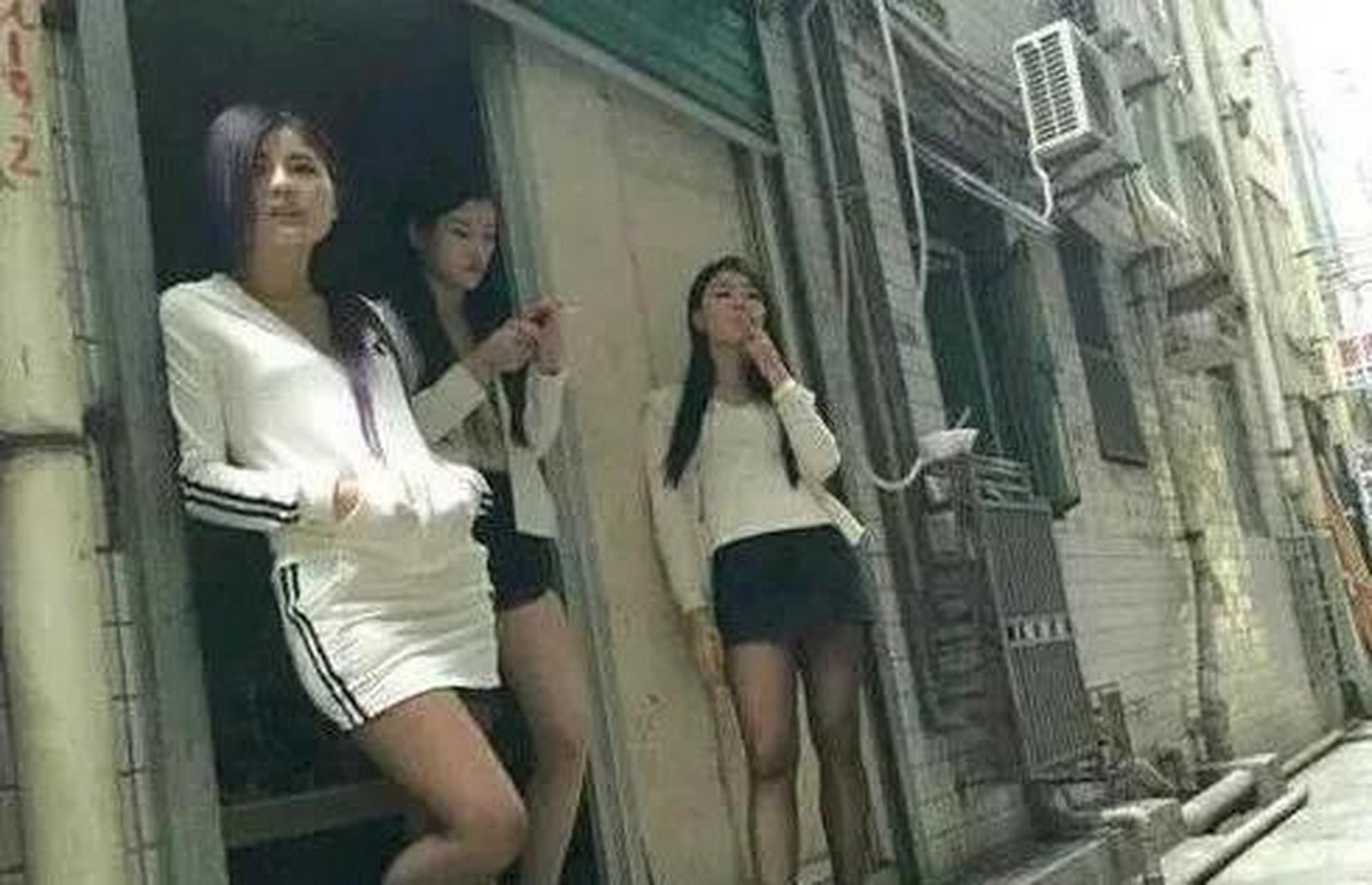 1990年,深圳街头的发廊小妹独自站在"洗头房"门前抽着烟.