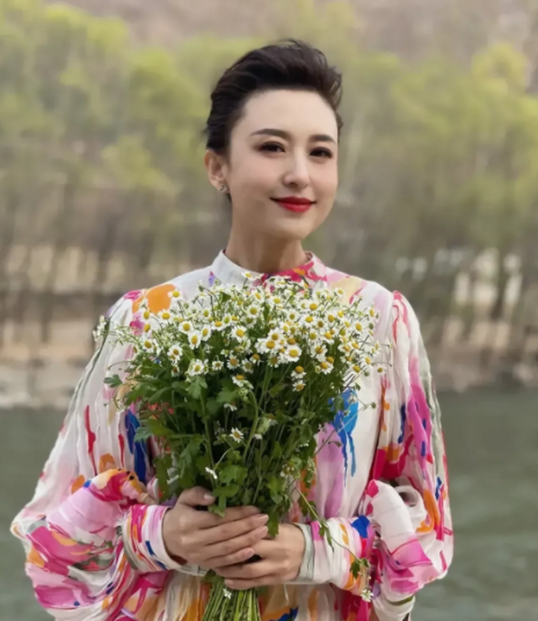 央视著名主持人张雷非常喜欢在户外拍照,她穿着一条带大花的长裙,手里