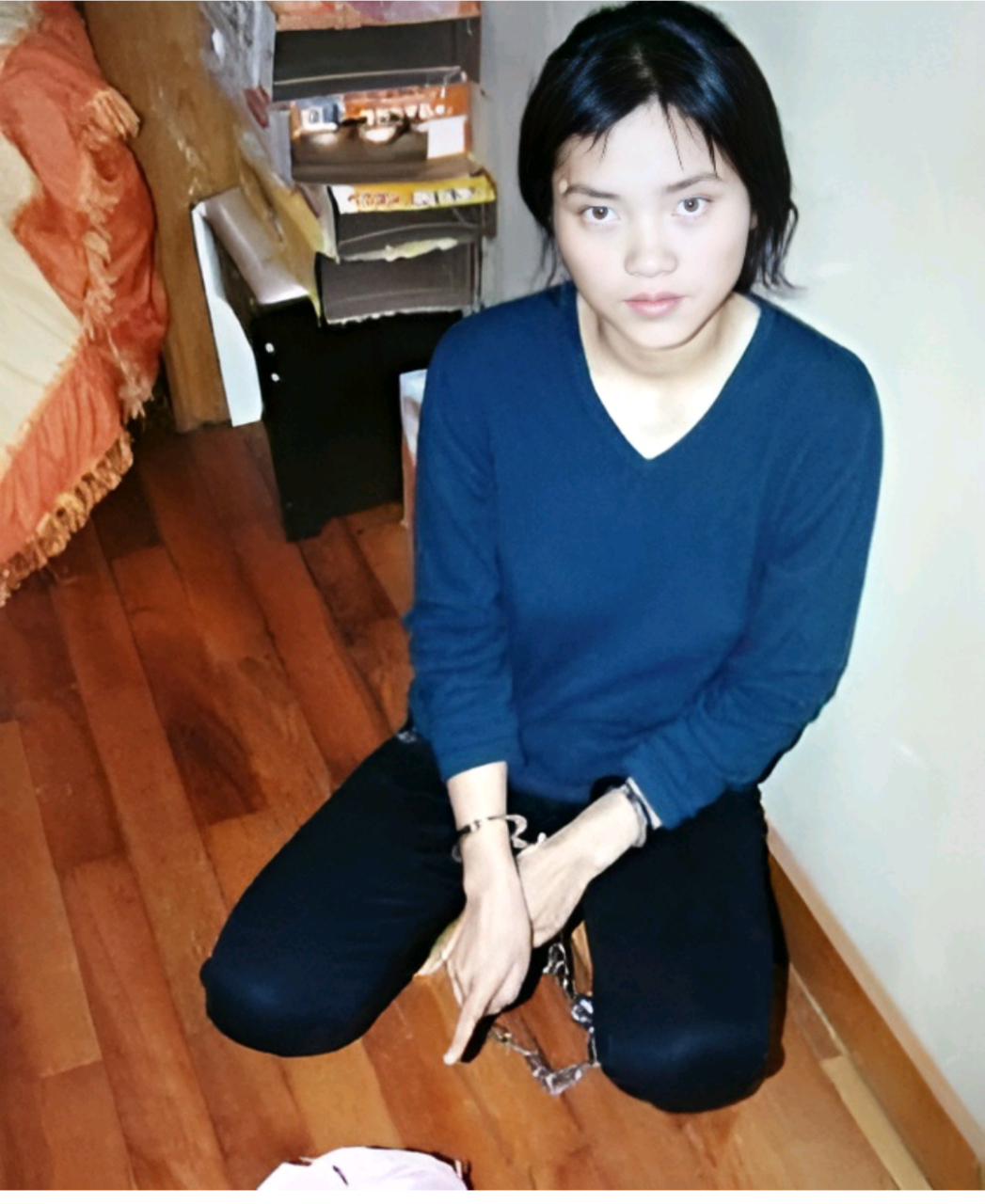 2008年,被捕后的毒贩杨菊芬,画面中的她被铐上手铐,面前的地面上放着