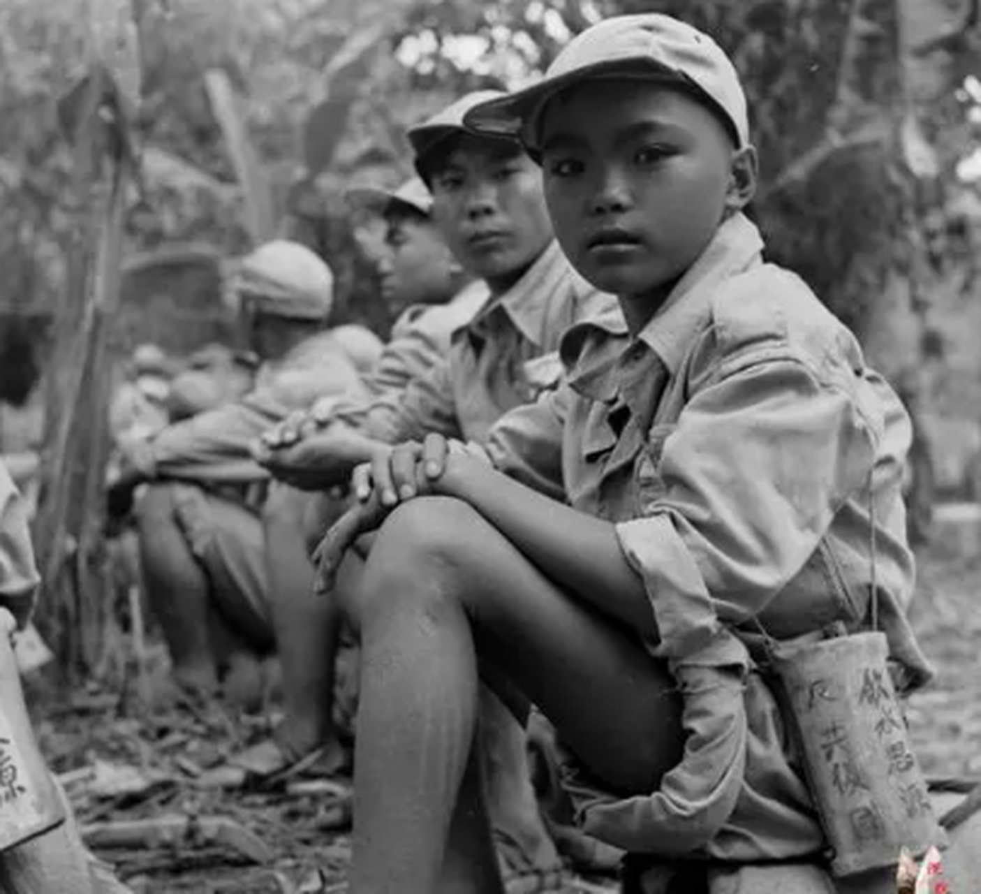 这张娃娃兵穿着远征军的棉服,脖子上挂着一个干粮袋,肩上有大水壶和