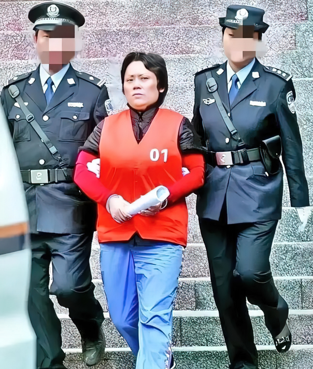 2009年,重庆"黑赌教母"谢才萍,被两名警察押送出席庭审,她短发凌乱