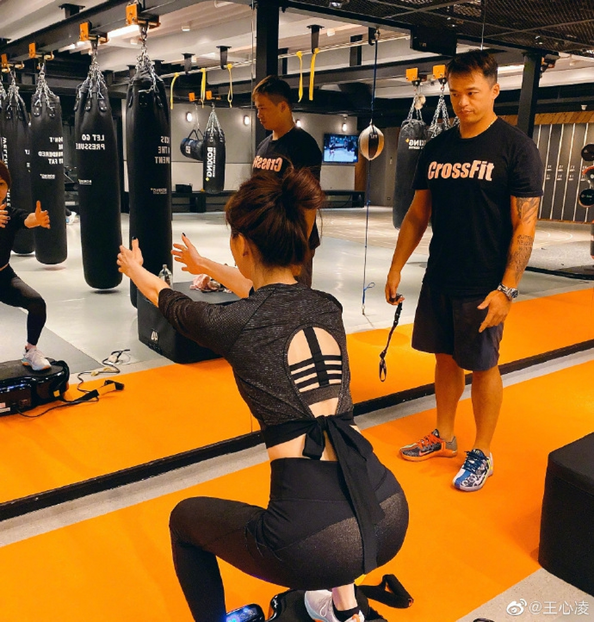 照片中,王心凌扎丸子头,身穿露脐运动装, 在健身房里认真练习手臂