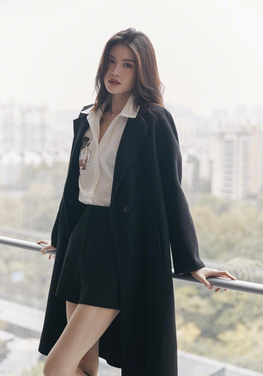 何穗和大衣真的是绝配 黑色羊毛大衣内搭唐老鸭印花衬衫,加上利落长靴