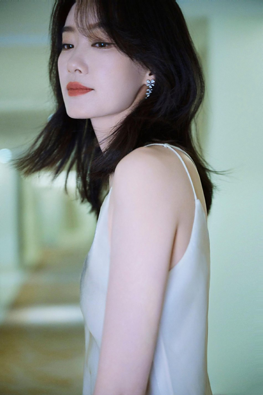 照片中,张小斐身穿白色丝绸吊带长裙秀美背,眼神迷人,发丝飘逸,女人味