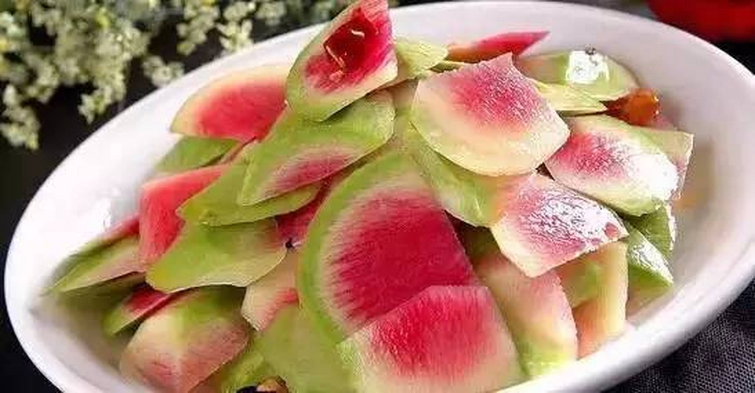 心里美萝卜洗净,用刀将萝卜皮削成片状; 萝卜皮削好了入盆中,撒少许盐