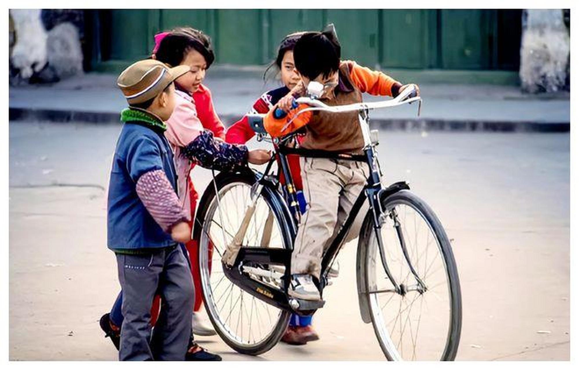在1987年的广西阳朔小街上,有个孩子骑着一辆二八大杠的自行车.