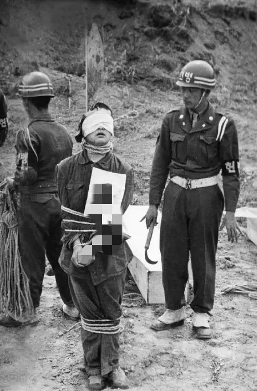 这是1950年,韩国宪兵处决犯人的现场,照片中的这个男子被绑在柱子上