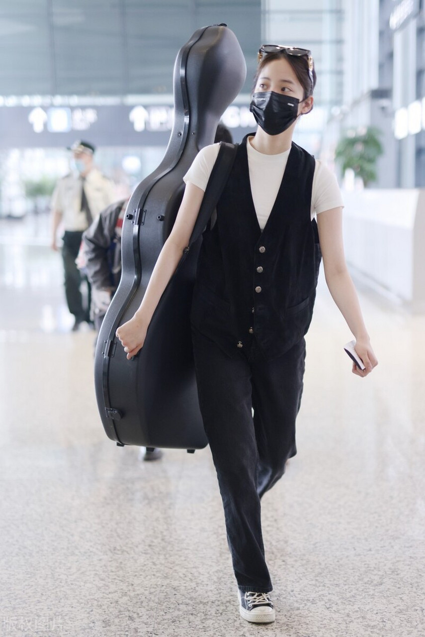 欧阳娜娜身背大提琴现身机场,黑色排口马甲搭配白色t恤,邻家少女的穿