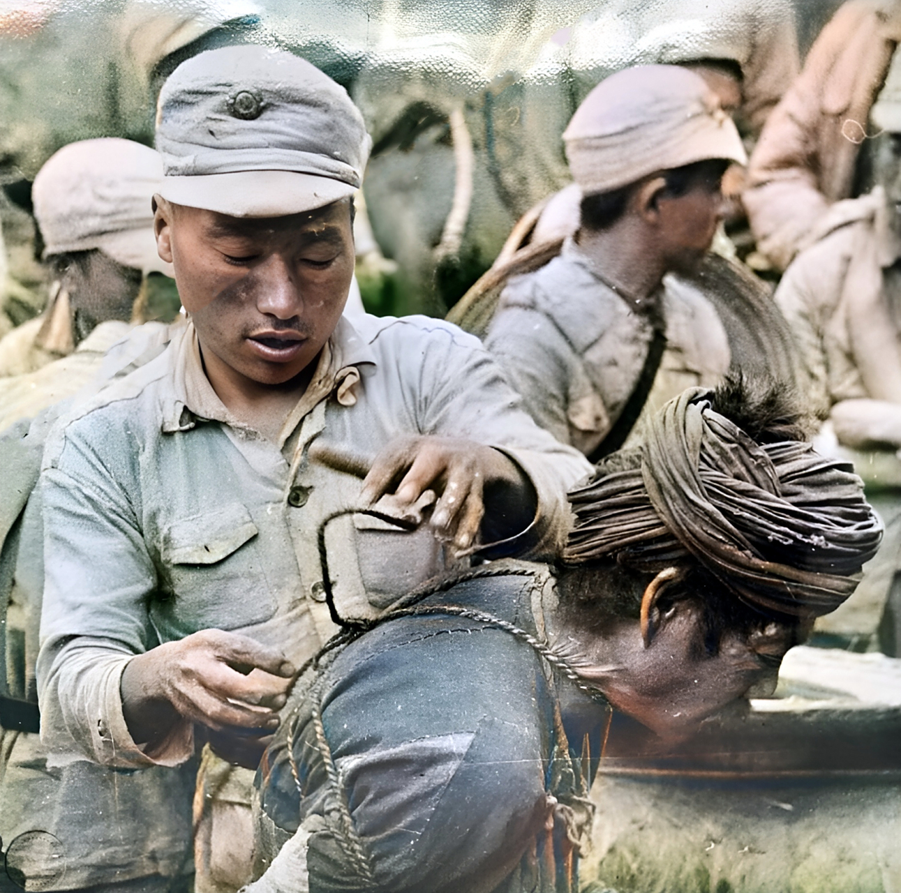 1944年,在滇南抗战中,一名国军士兵正为当地的一位老汉解开绑在身上的