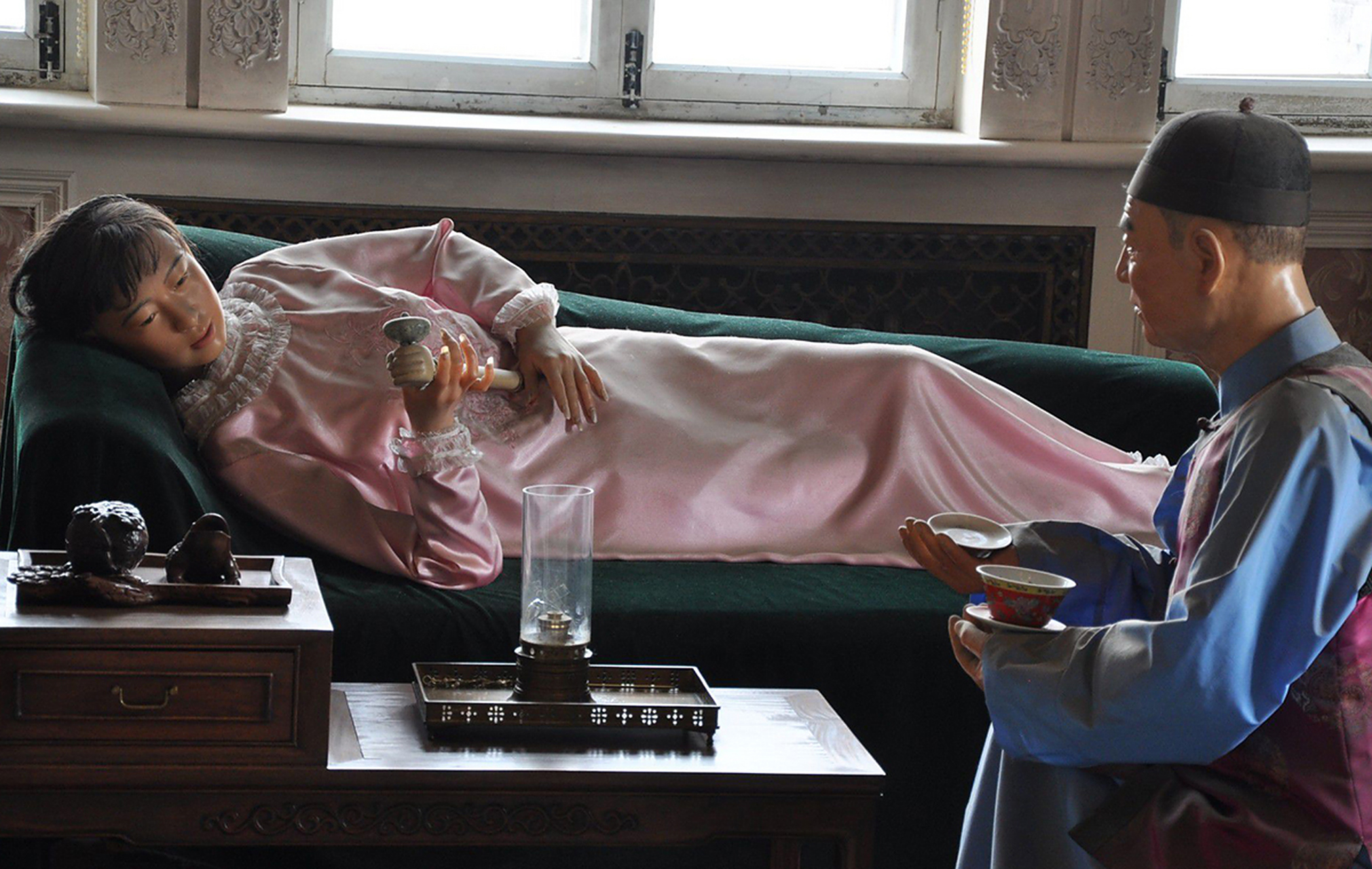 照片中的两个女子,慵懒地躺在床上,不停地吸食鸦片,看起来似乎很享受