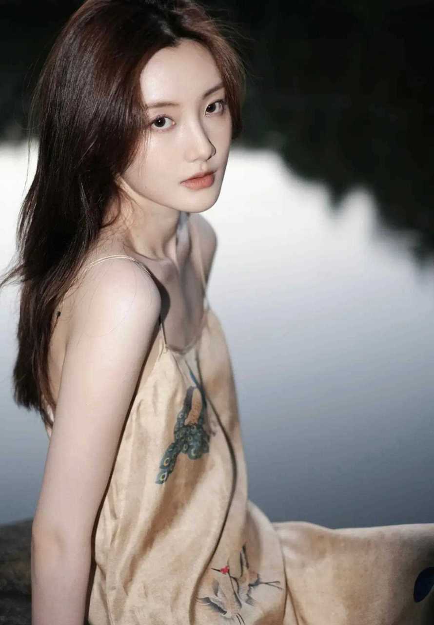 这个叫张乔耳的新生代女演员身穿一条丝绸吊带裙,披肩长发,在水畔静坐