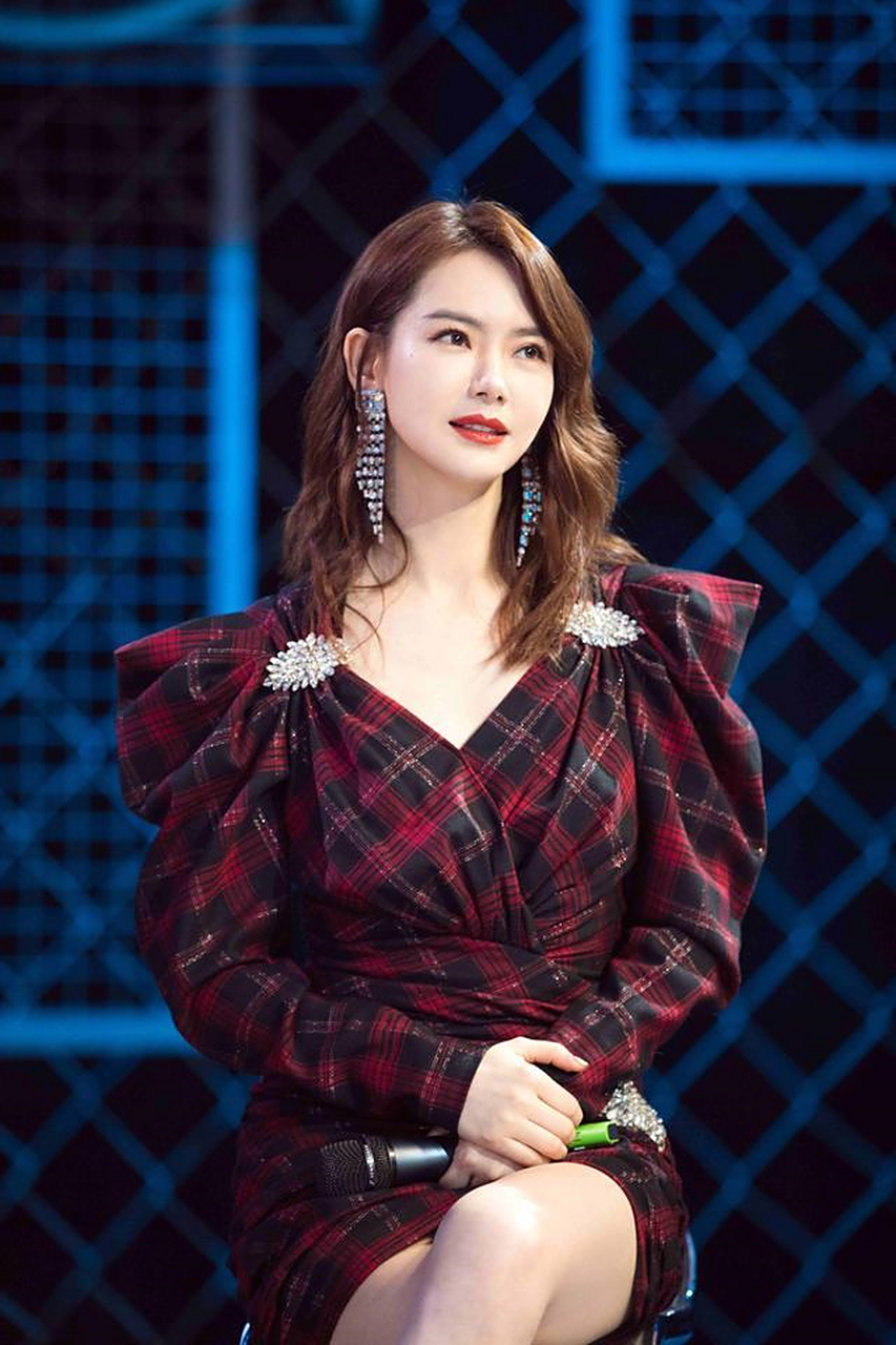 戚薇的v领连衣裙,红黑格纹的设计,肩膀用了垫肩与褶皱灯笼袖的处理,彰