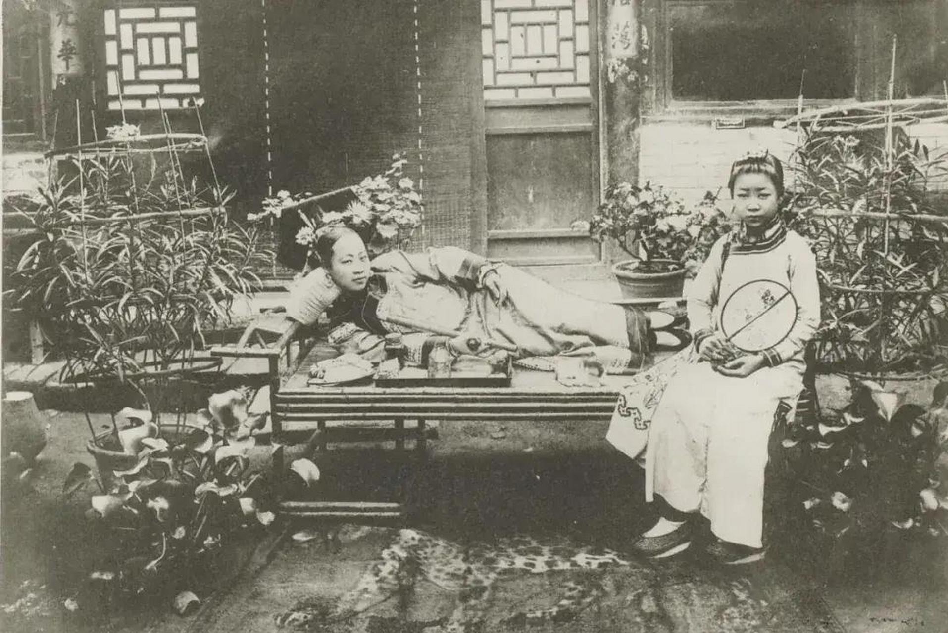 清朝满族大户人家的女子,在自家庭院门口罗汉床上抽鸦片的场景.
