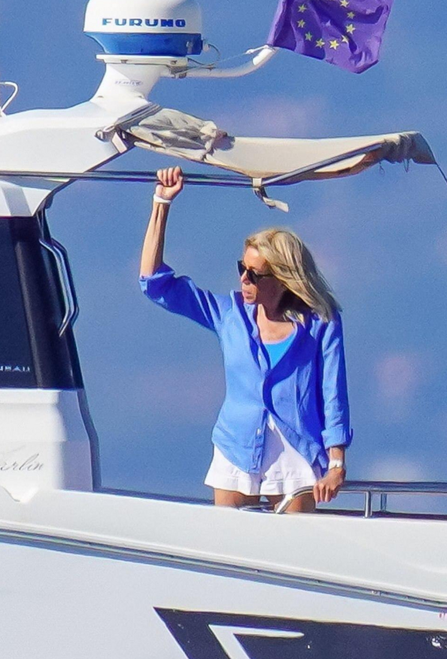 她与马克龙度假,穿着带袖的泳衣,坐在游艇上后背消瘦,头戴棒球帽不像