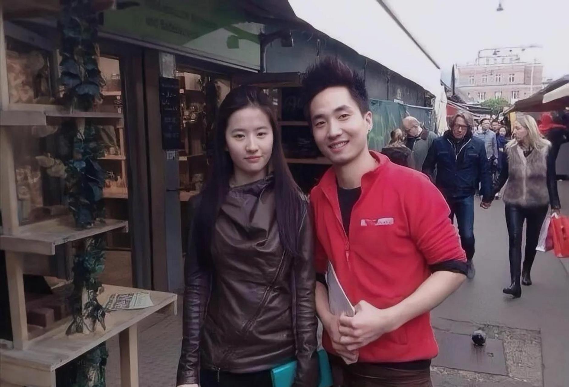 刘亦菲和粉丝合影照,虽然刘亦菲一手拿着钱包,一手拿可口可乐,但是