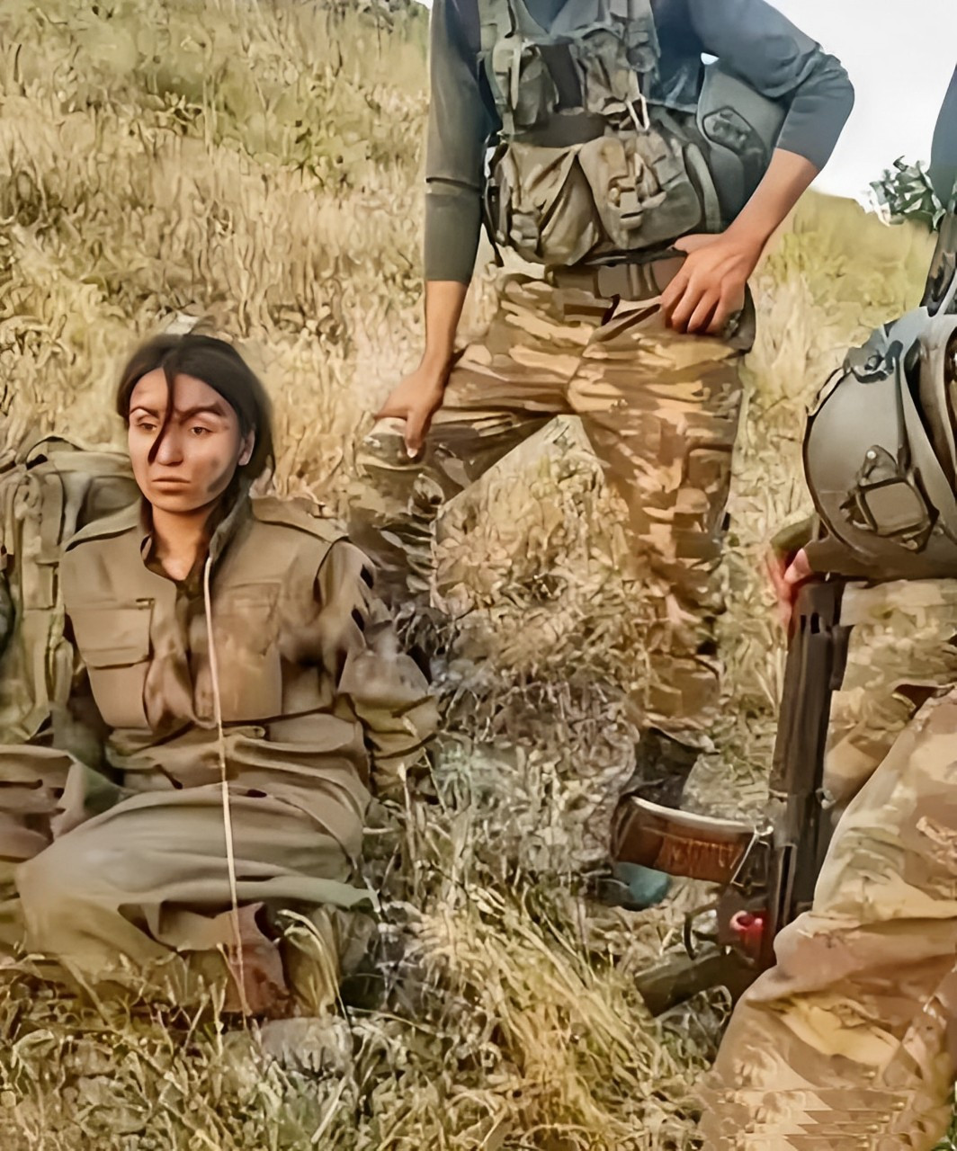 一名库尔德女兵被土耳其士兵俘虏的照片,女兵脸上露出麻木的表情,她