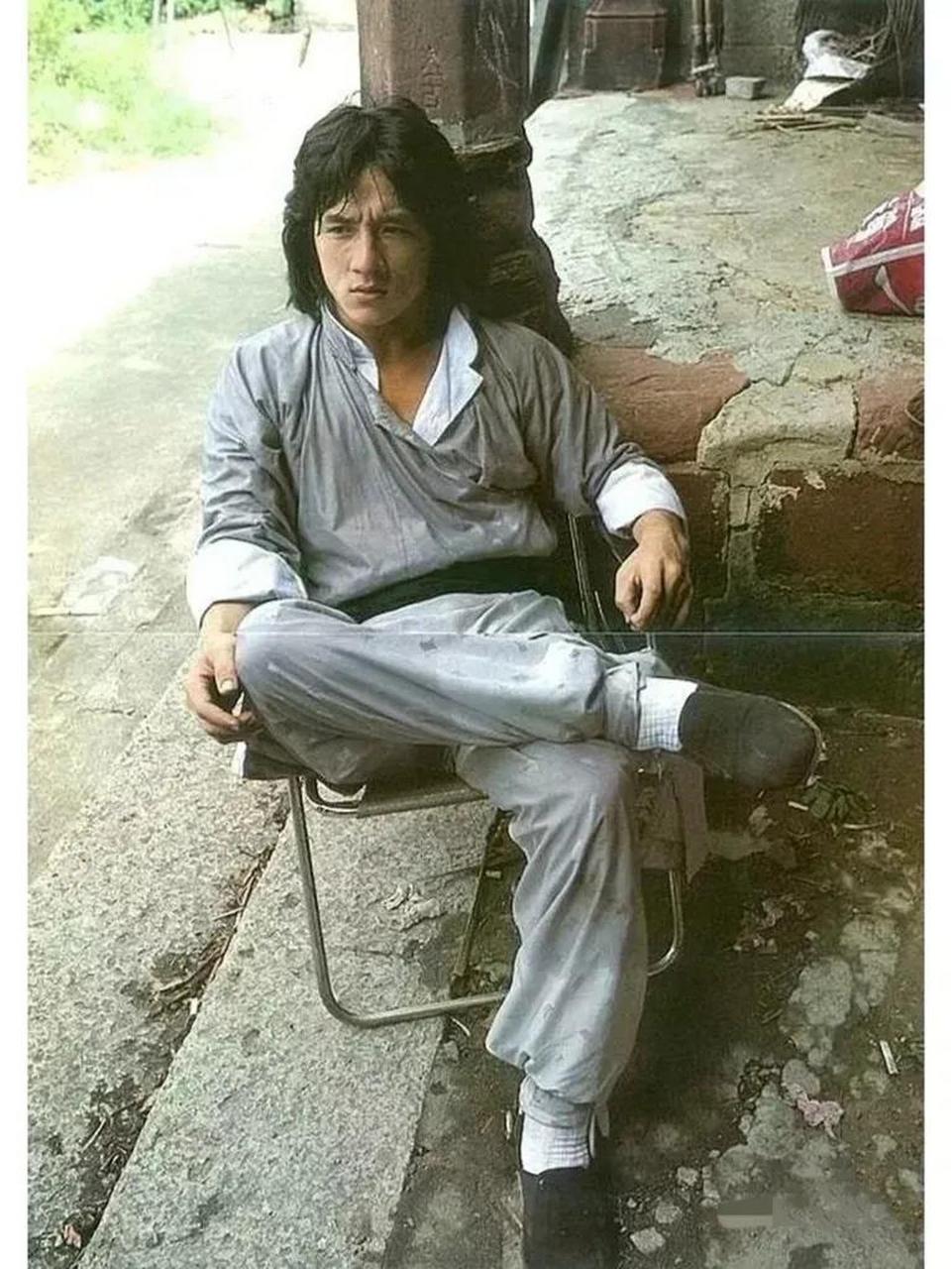 1980年,有一张年轻的成龙坐在椅子上休息的照片,展现了他年轻帅气的一