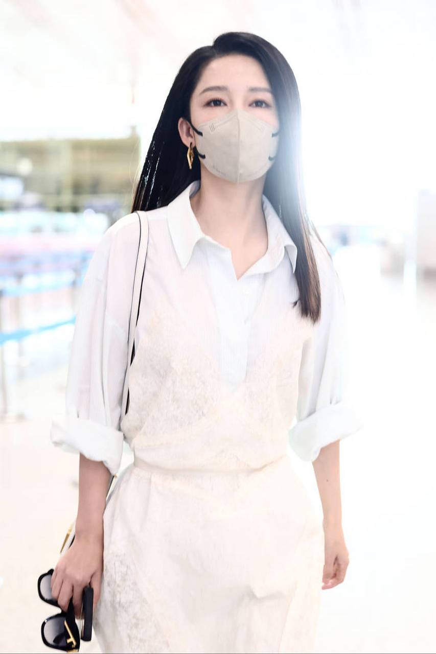 近日工作室曝光了一直李沁机场路透照片,李沁穿着整套白色衬衫裙的