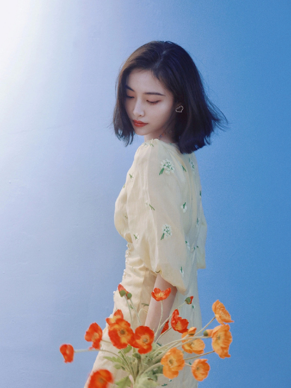 许佳琪最新时尚造型,身穿淡黄色碎花连衣裙在蓝色墙面的映衬下更显