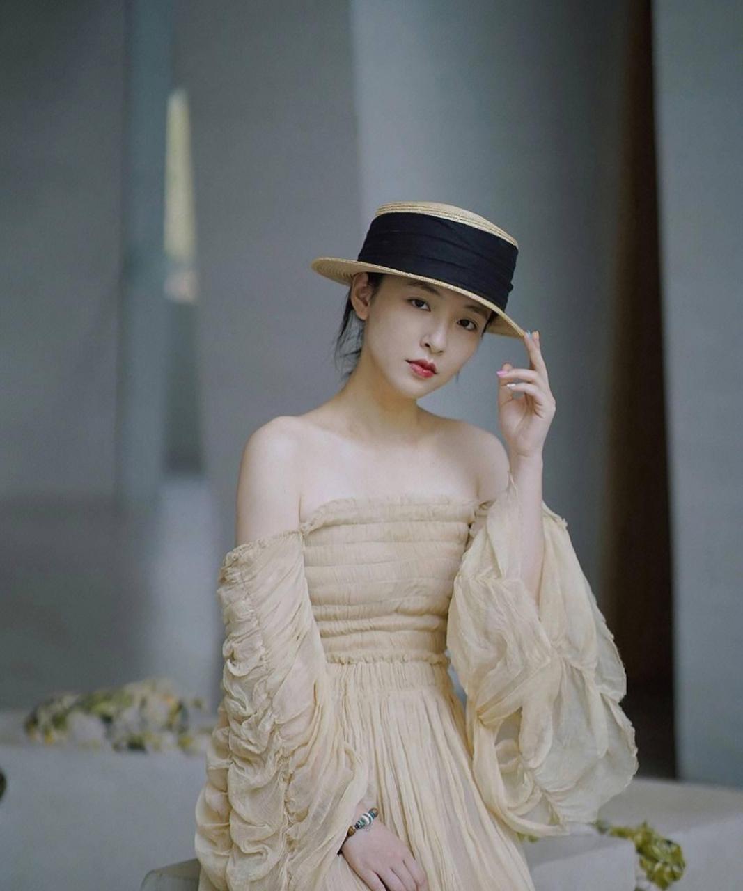 吴倩身穿米色露肩纱裙,手拉裙摆轻舞俏皮灵动.