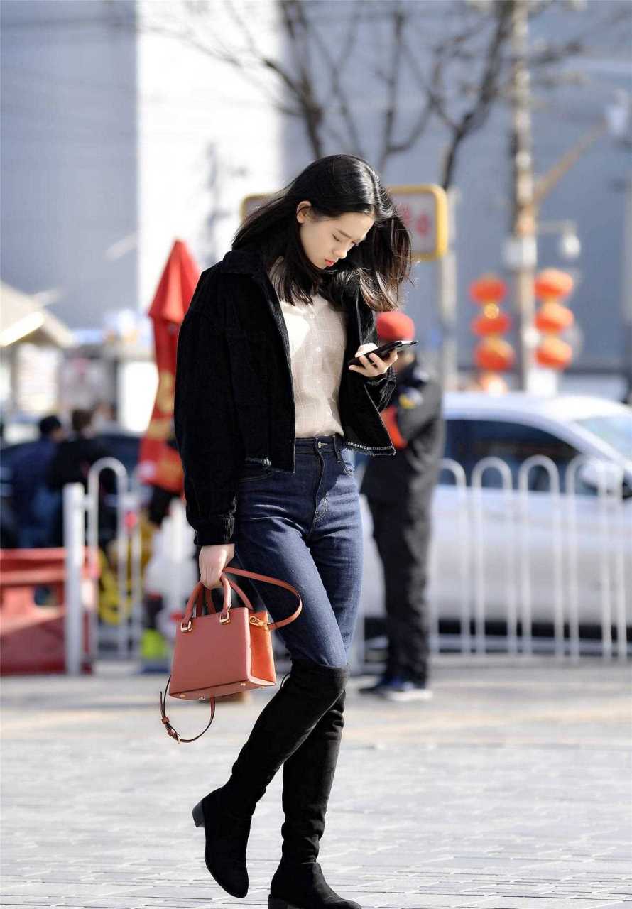 黑色过膝长靴,搭配深蓝色的紧身牛仔裤,搭配短款的夹克,衣襟短一些