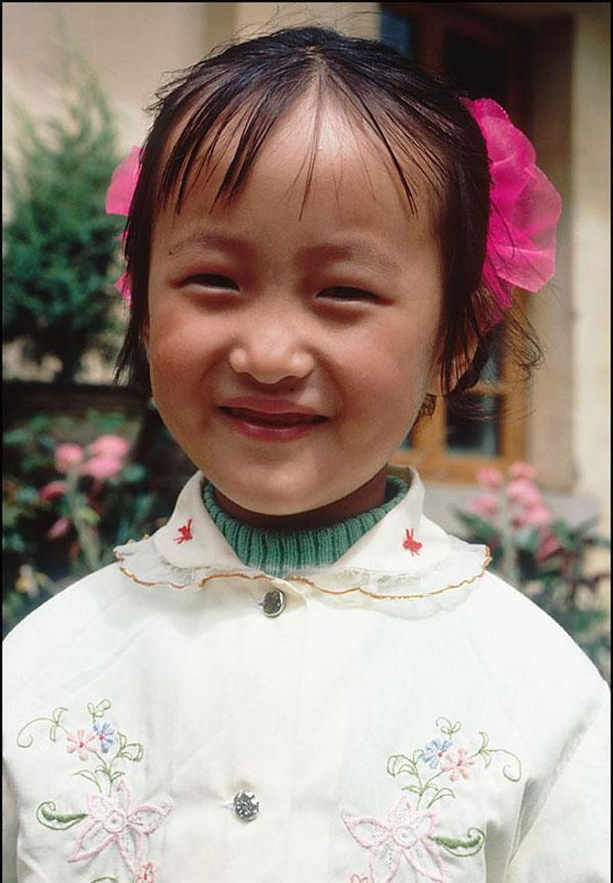 图为90年代#大理#城中的一个小女孩,面对镜头她笑的很可爱,这张照片