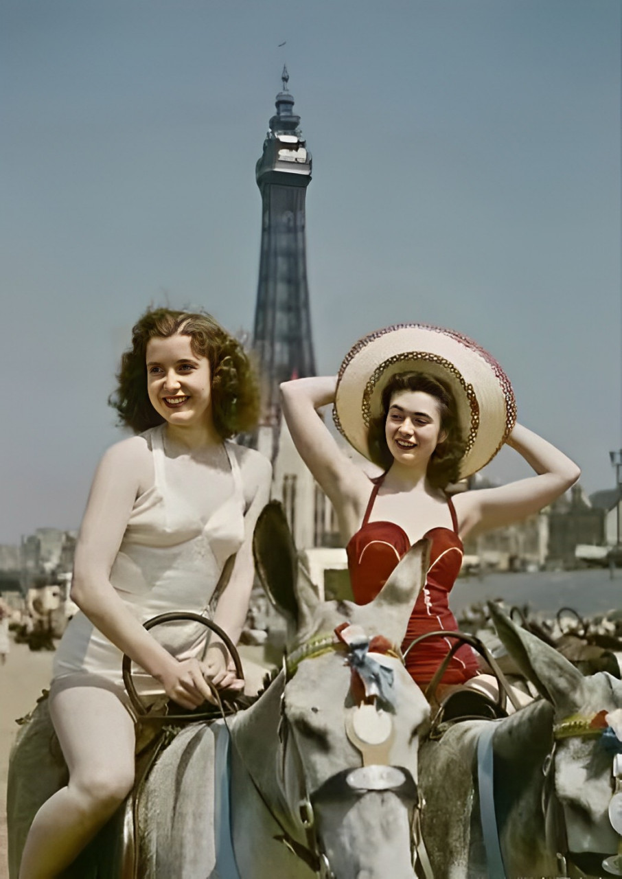 穿白色泳衣的女子可能是第一次骑马,在工作人员的帮助下才能上马.